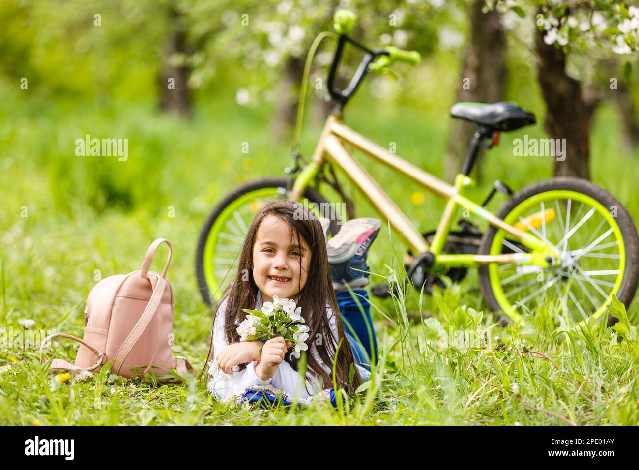 Portrait of a smiling little girl lying on green grass Stock Photo - Alamy