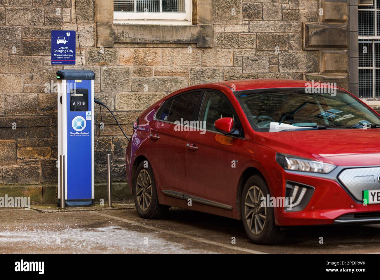 A red electric vehicle plugged in at a ChargePlace Scotland EV charging