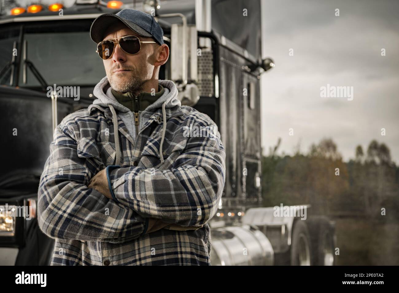 Caucasian Semi Truck Driver in His 40s and His American Tractor. Transportation Industry. Stock Photo
