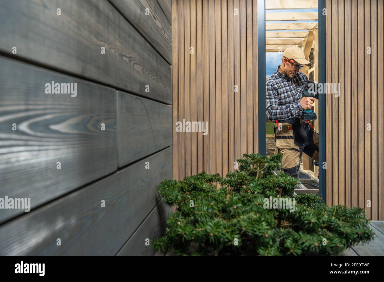 Modern Custom Garden Shed Building Performed by Caucasian Construction Worker in His 40s. Window Installing. Small Architecture Theme. Stock Photo