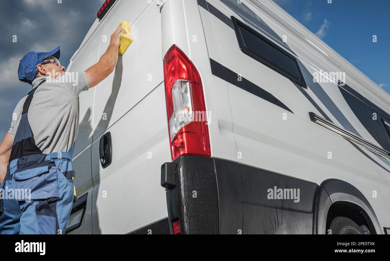 Preparing RV Camper Van For the Season. Caucasian Man Washing His Motorhome Using Sponge and Cleaning Detergent. Stock Photo