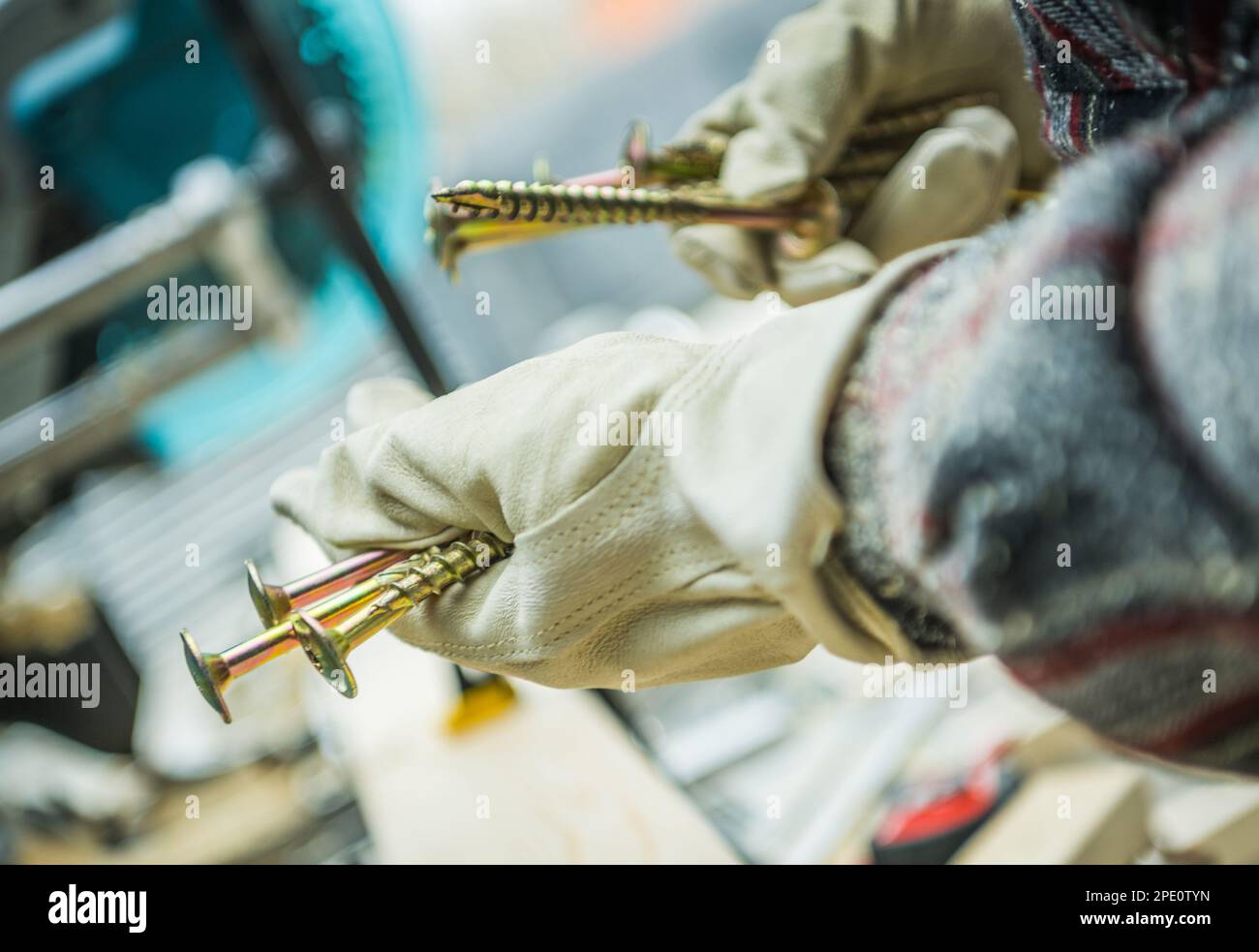 Wood Material Coarse Threaded Screws in Contractors Hands. Protective Gloves Wearing. General Construction Theme. Stock Photo