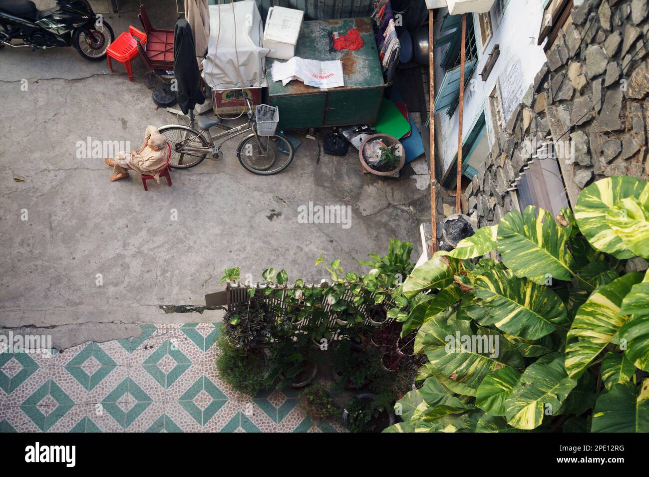 Ho Chi Minh City, Vietnam - July 4, 2019: Old Vietnamese lady sitting in a yard and observing. Elder Asian woman wearing pajamas top view Stock Photo