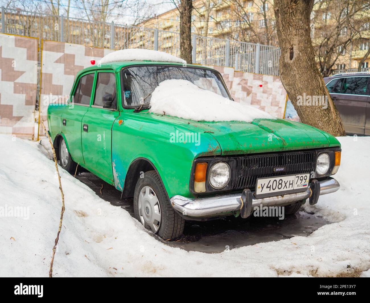 Moscow. Russia. March 15, 2023. Old vintage green soviet car Izh Moskvich covered with snow on a spring day in a Moscow courtyard. Stock Photo