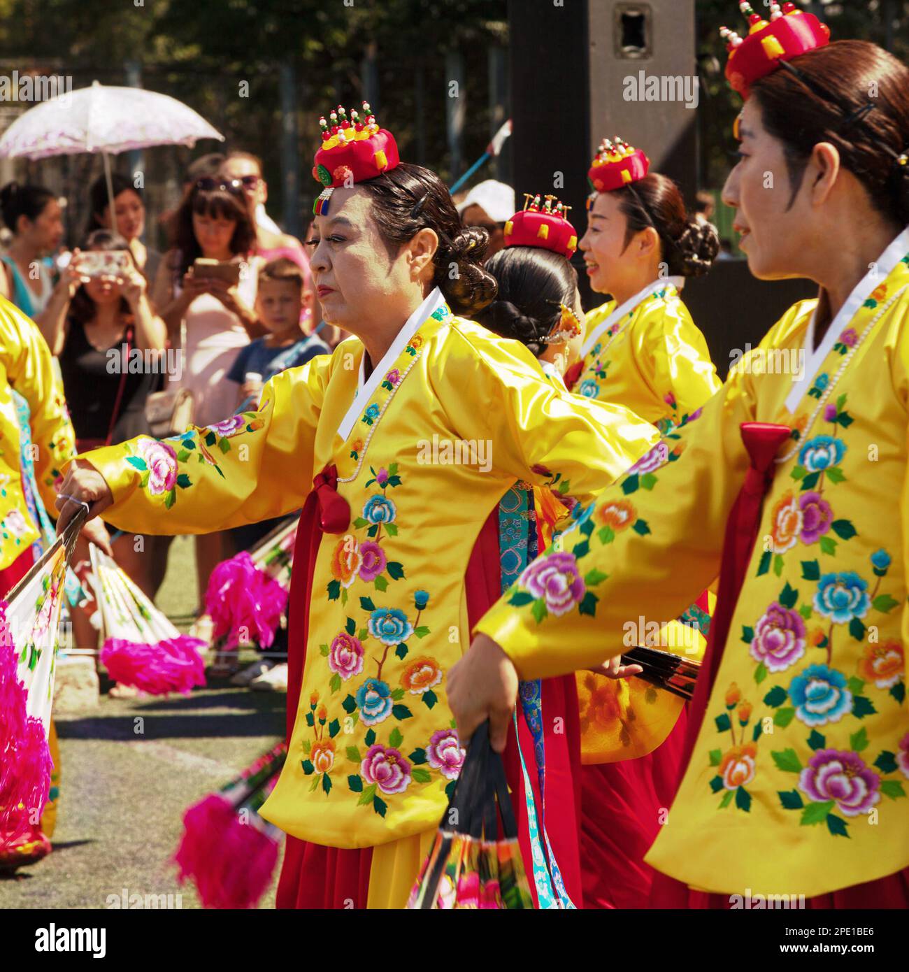 Khabarovsk, Russia - August 13, 2017: Korean traditional dancers. Old ladies wearing colorful yellow and pink dresses, dancing Buchaechum or fan dance Stock Photo