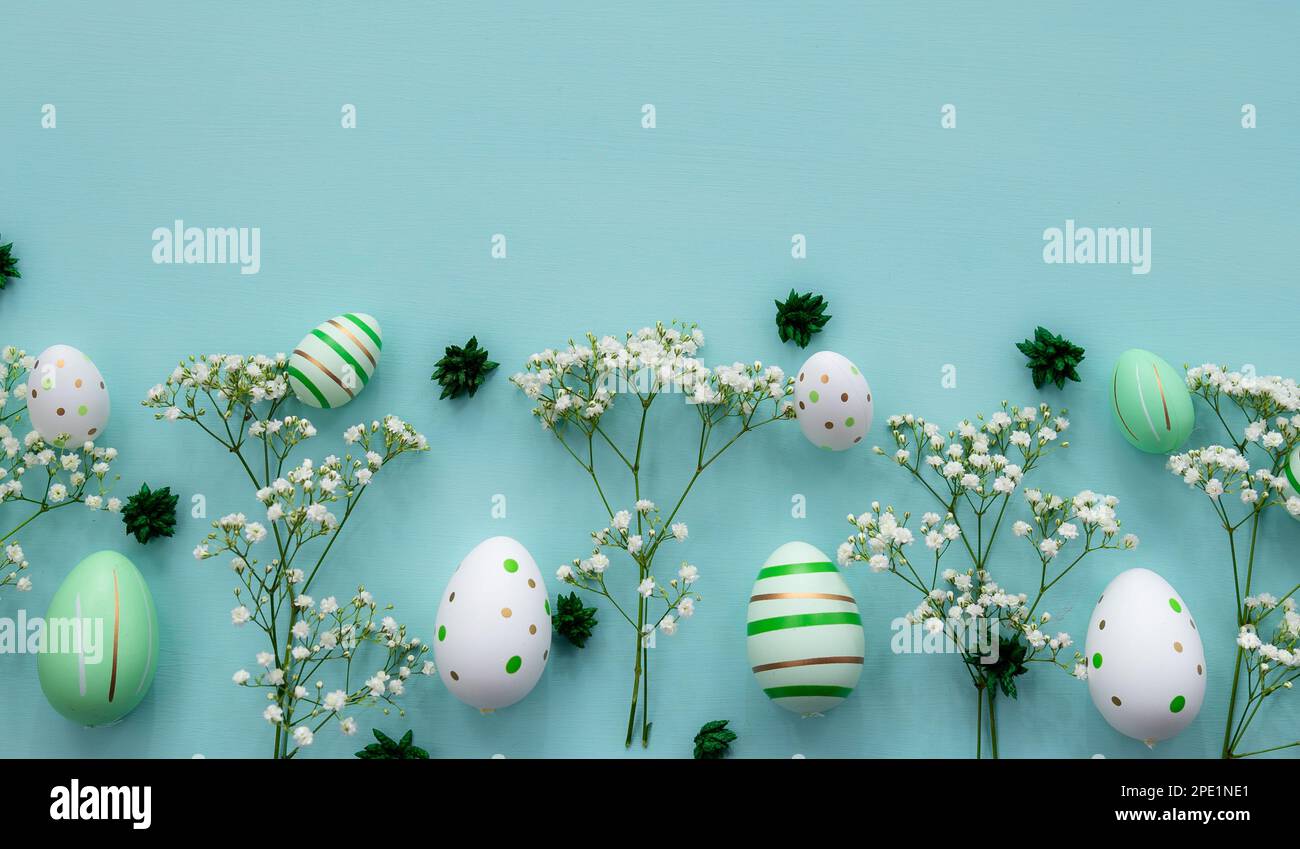 Flat lay easter composition with flowers and eggs on a green background ...