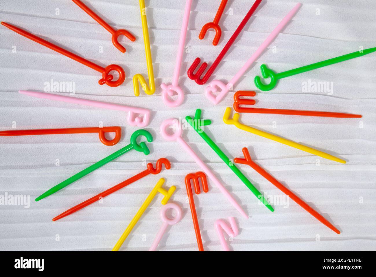 Colorful plastic sticks with English letters on top scattered on white. Word ok in the center. Fun educational toy for kids learning alphabet Stock Photo