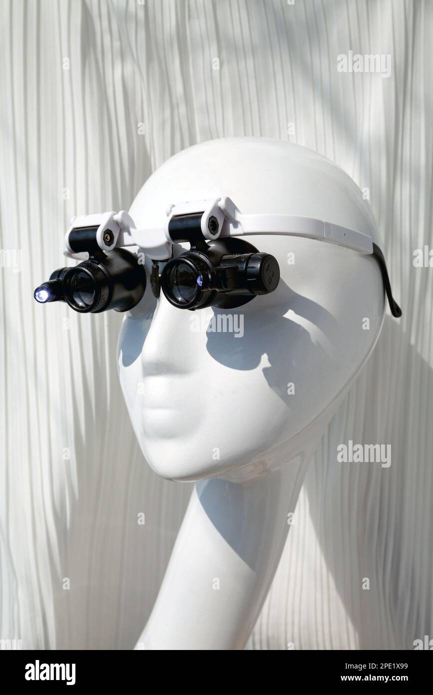 Mannequin wearing double eye magnifying glasses with LED light illumination. High magnification lens handsfree glasses for professionals, specialists, Stock Photo