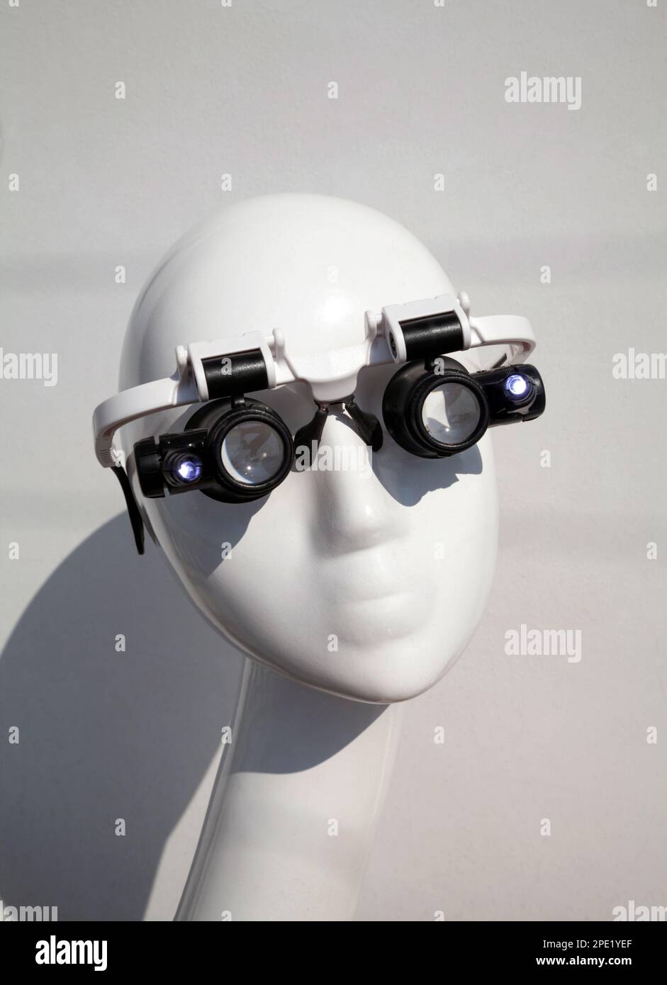 Mannequin wearing double eye magnifying glasses with LED light illumination. High magnification lens handsfree glasses for professionals, specialists, Stock Photo