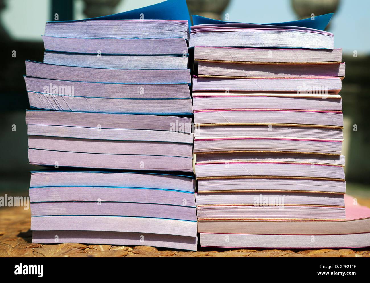 Many cheap small notepads in 2 stacks seen from a side. A pile of blue