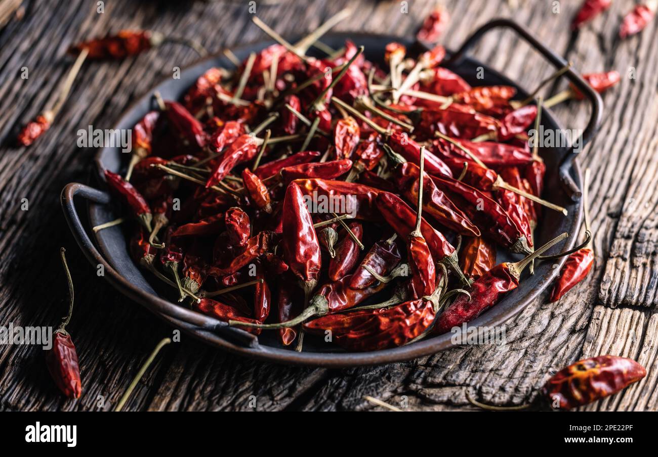 Dried chili peppers in a tin tray on a rustic table. Stock Photo