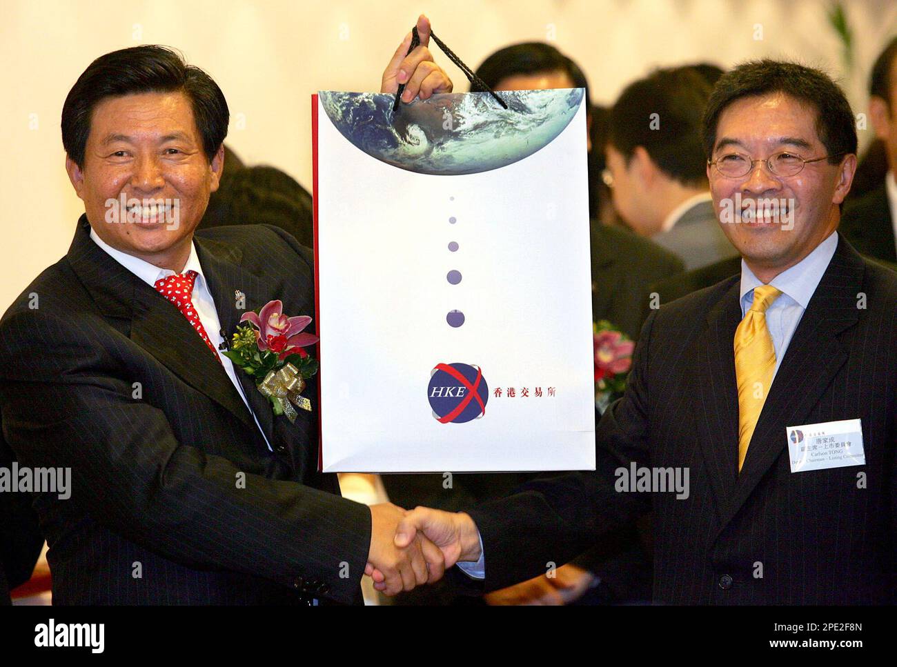 China COSCO Executive President and CEO Wei Jiafu, left, raises a gift  package as he shakes hands with Carlson Tong, right, listing committee  deputy chairman of Hong Kong Stock Exchanges at the