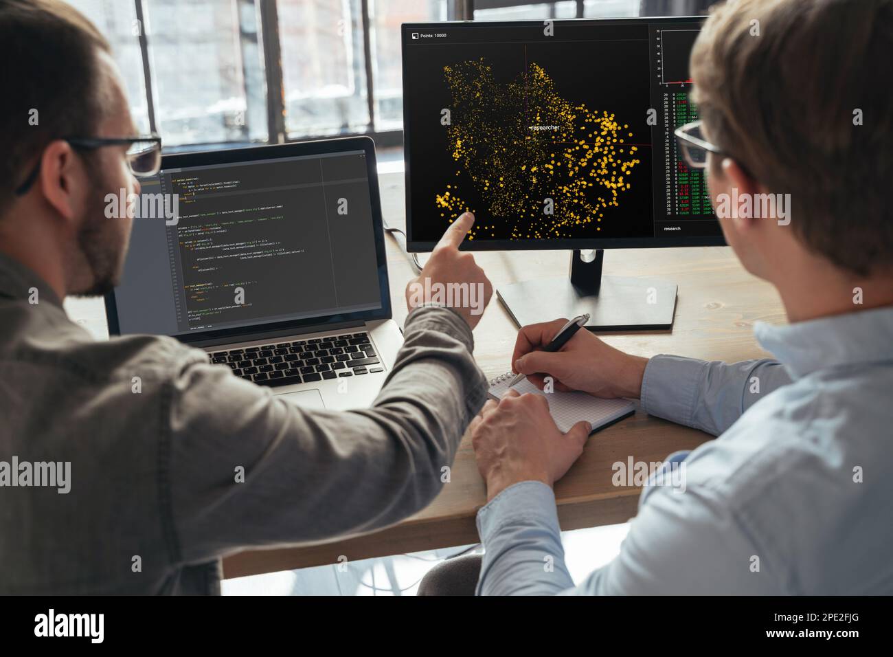 Closeup of two men data science specialists working at office together, analyzing big data on screen. Coders working on new project  Stock Photo