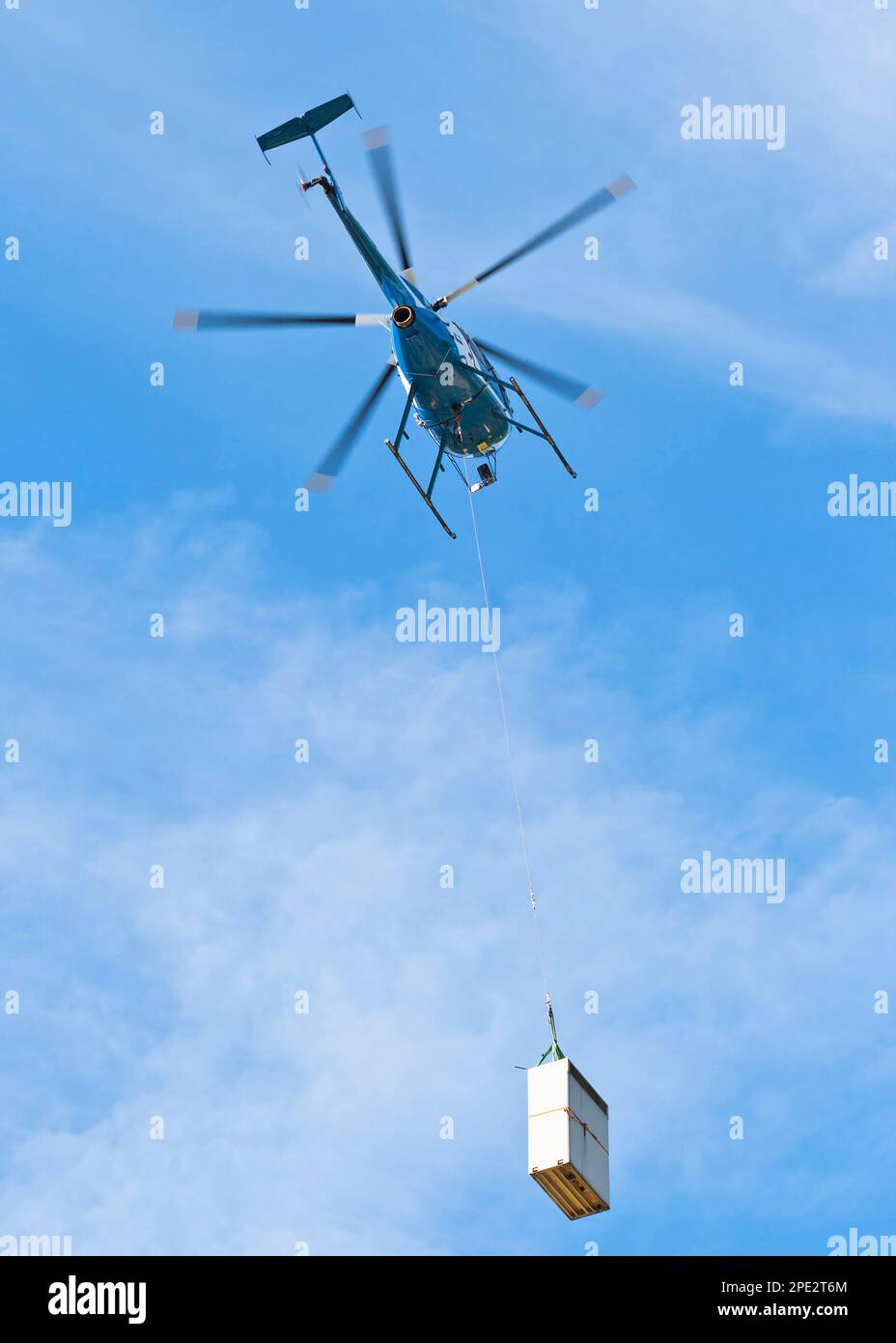 Bottom view of helicopter with cargo flying in the blue sky Stock Photo