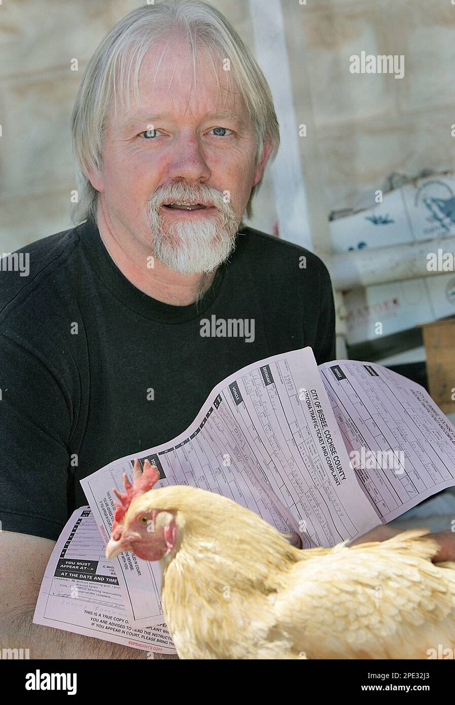 ADVANCE FOR THE WEEKEND OF JUNE 25-26 ** Jeff Harris holds three citations  that he received from the city of Bisbee, Ariz., along with one of his  numerous chickens, April 14,