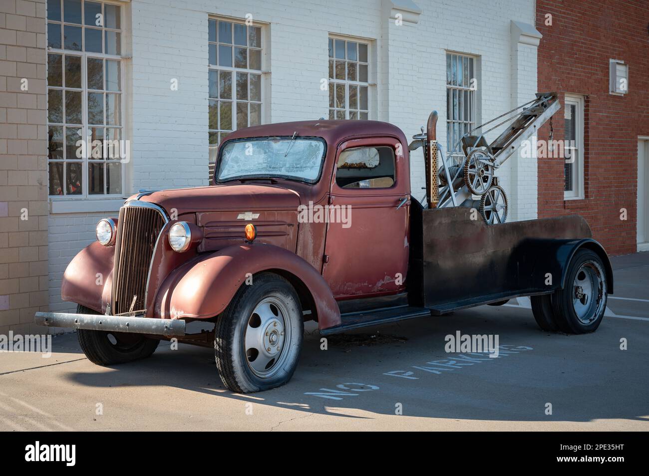 An aged rusted truck is parked in front of a building, its vintage body