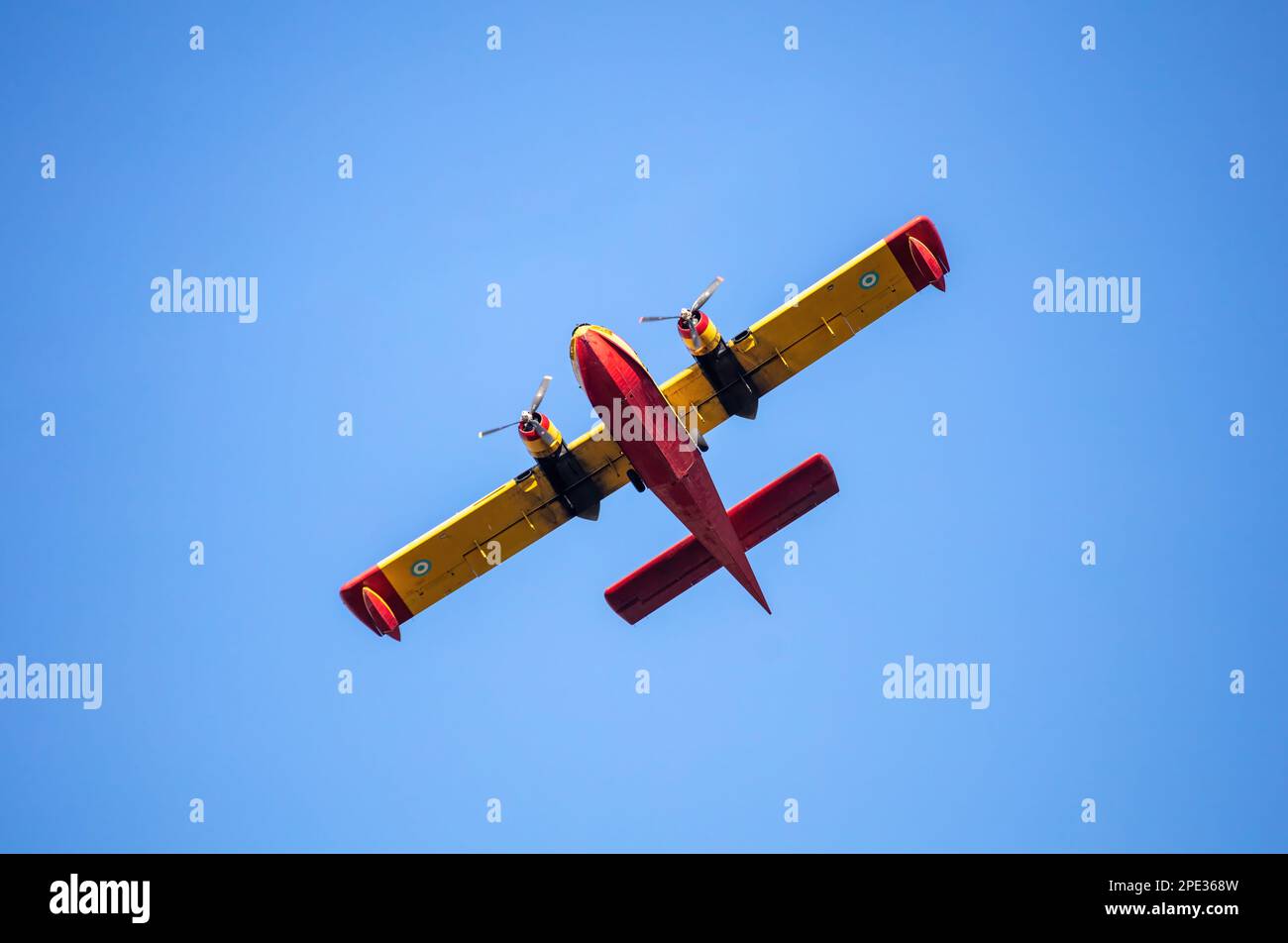 Canadair Firefight Aircraft, Scooper flying on blue sky background, under view. Yellow red color seaplane flight for rescue and transport. Stock Photo
