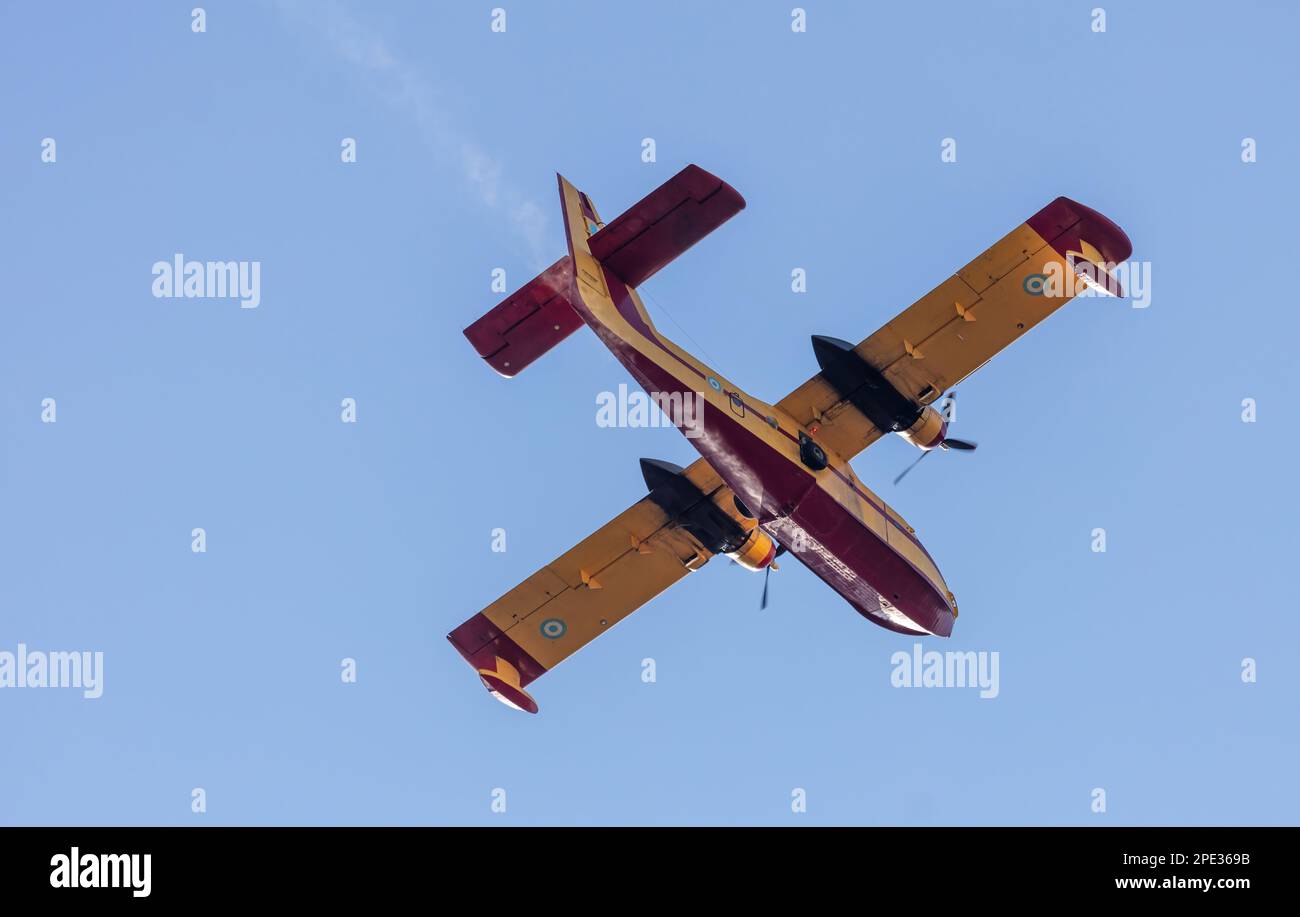 Canadair Firefight Aircraft, Scooper flying on blue sky background, under view. Yellow red color seaplane flight for rescue and transport. Stock Photo
