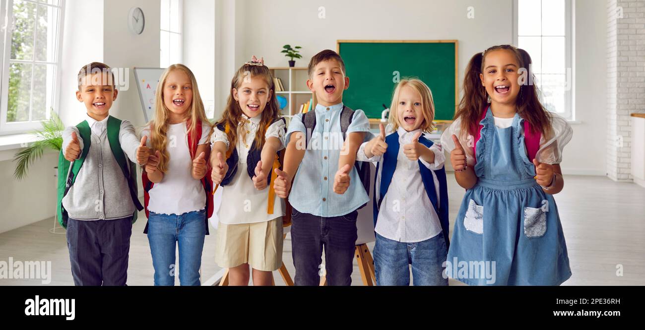 Happy group elementary school students showing thumbs up standing ...