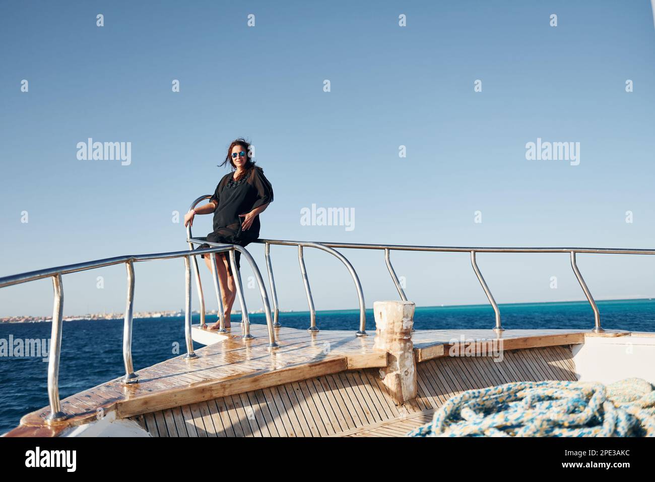 Mature woman standing on the yacht and enjoying her vacation on the sea Stock Photo