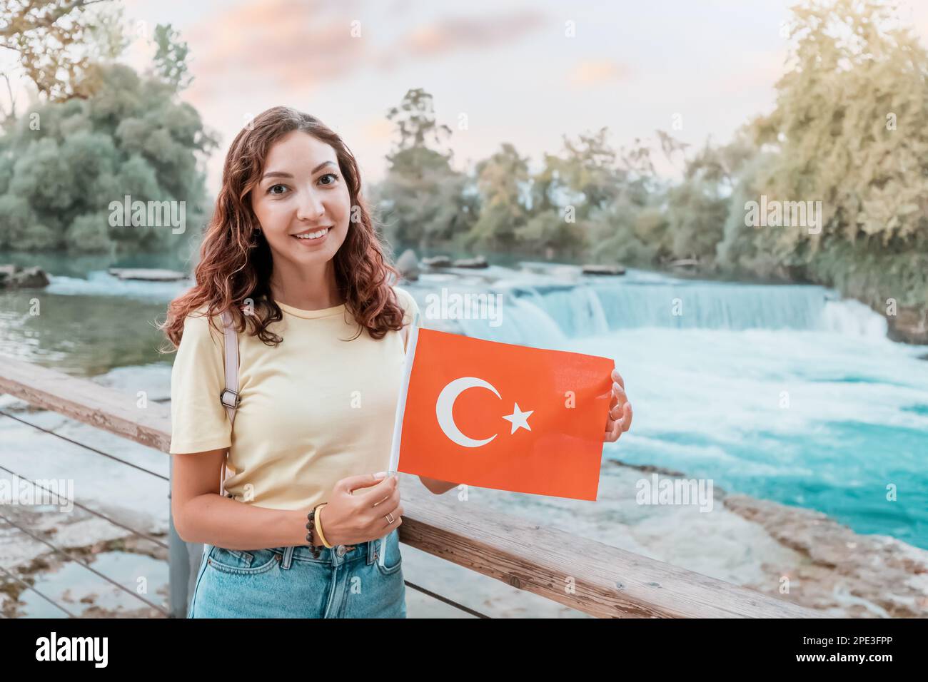 Girl with turkish flag standing near Manavgat waterfall. Travel attractions and natural landmarks in Turkiye Stock Photo