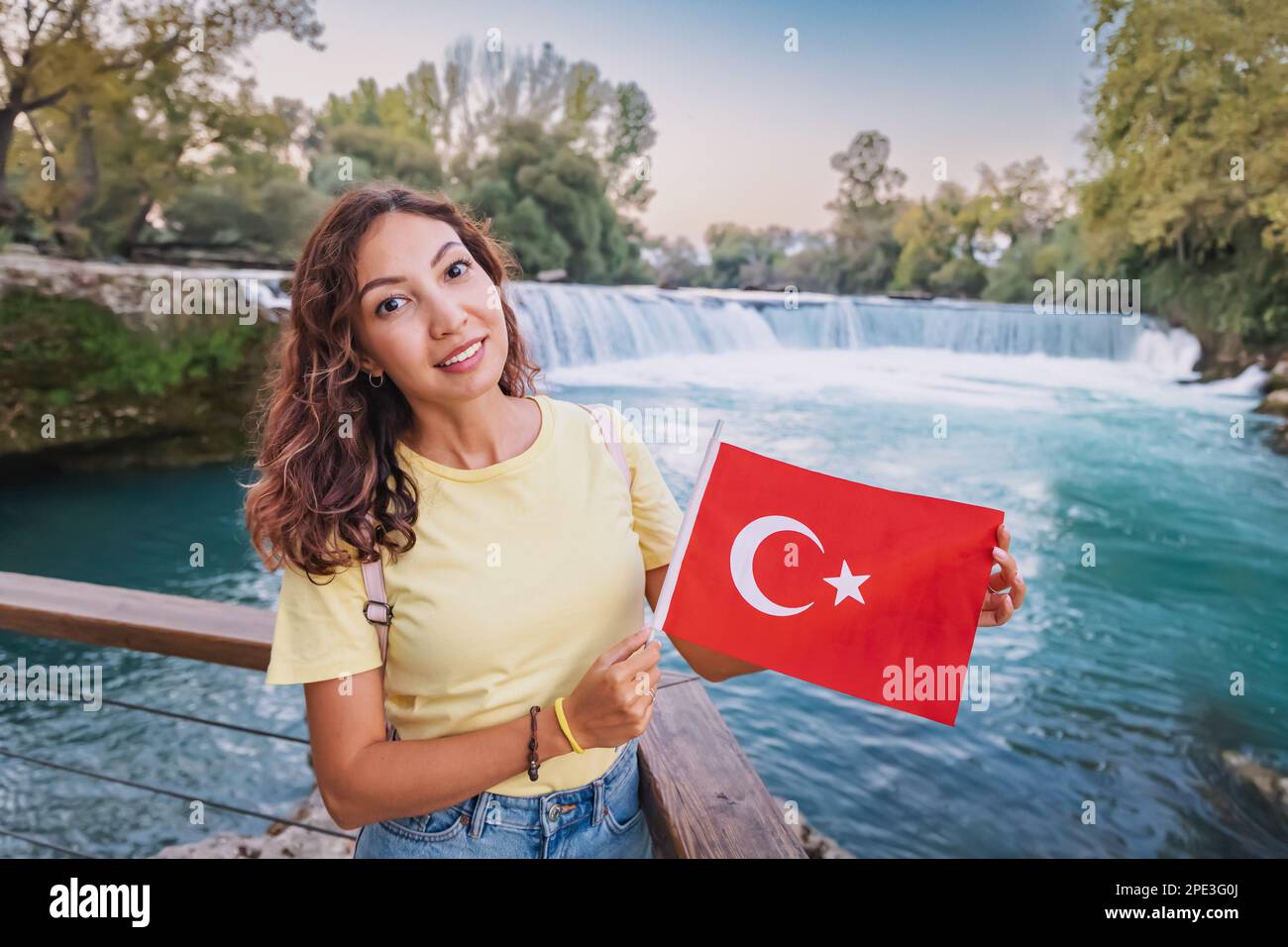 Girl with turkish flag standing near Manavgat waterfall. Travel attractions and natural landmarks in Turkiye Stock Photo