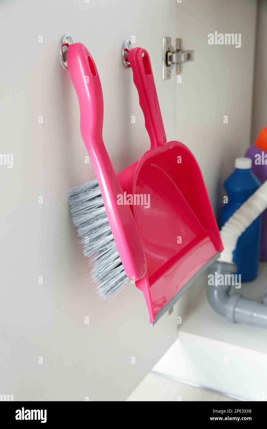 Brush and dustpan hanging on door. Cleaning tools Stock Photo