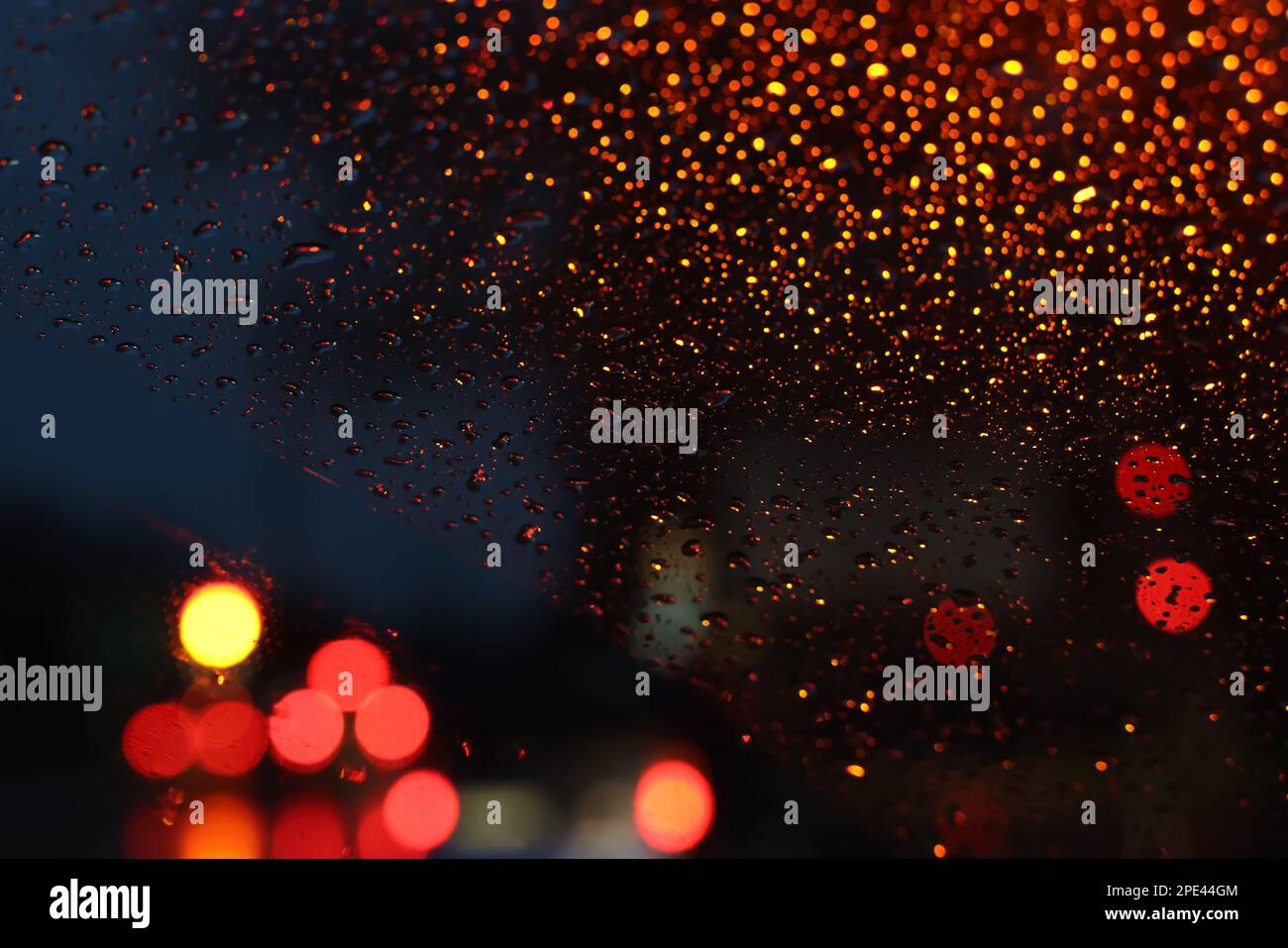 Blurred view of road through wet car window at night. Bokeh effect ...
