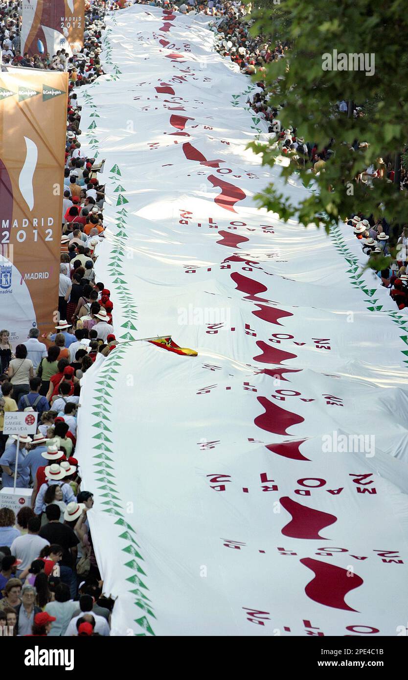 Some of the in total 1,500 volunteers carry a flag measuring 2.5 kilometers  (1.55 miles) long and 6.4 meters (21 feet) wide, described as the world's  biggest flag, along the Castellana boulevard