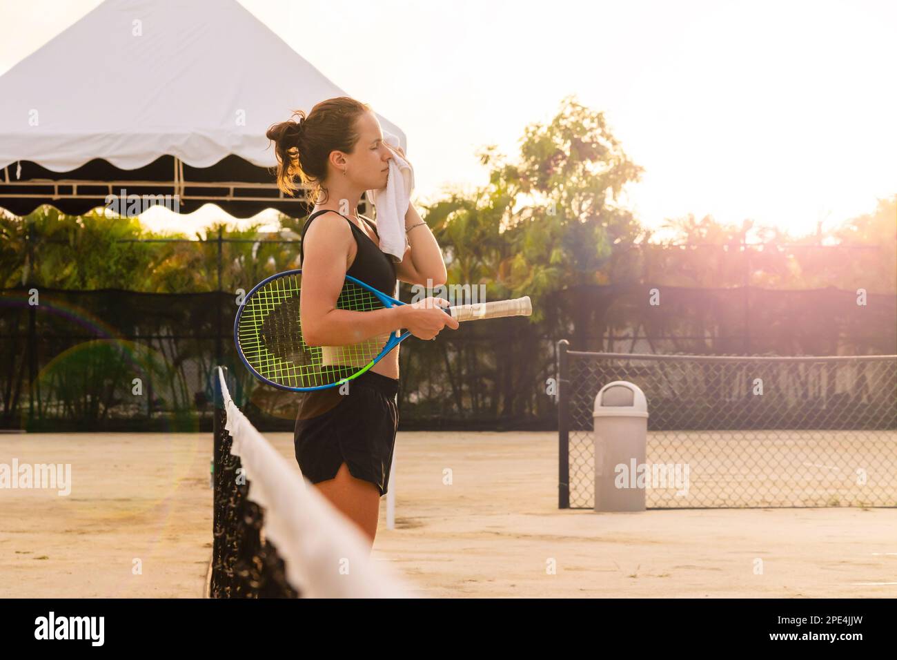 Woman athlete tennis player wiping her face with towel while standing