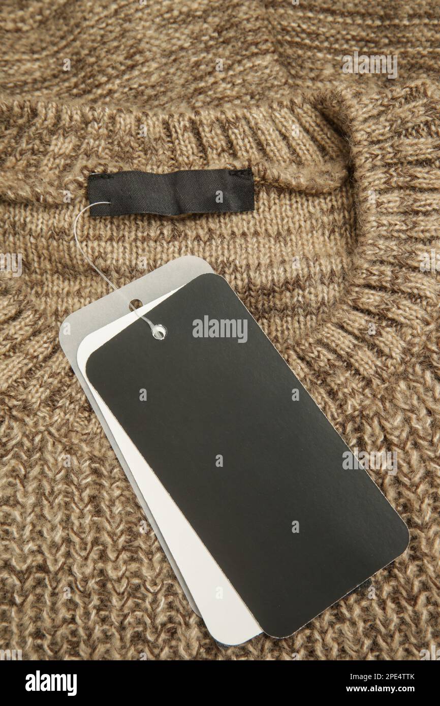 Close up of price tag of clothing item. Blank label tag mockup on a clothes. Fashion industry and retail concept. Stock Photo