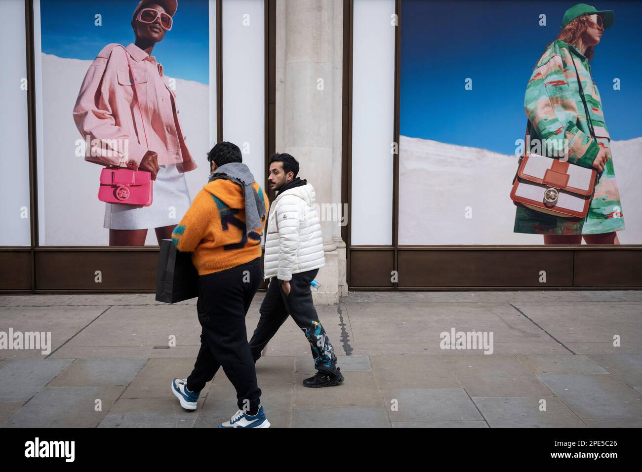 A family walk beneath imagery for accessories brand Longchamp on Regent Street, on 13th March 2023, in London, England. Stock Photo