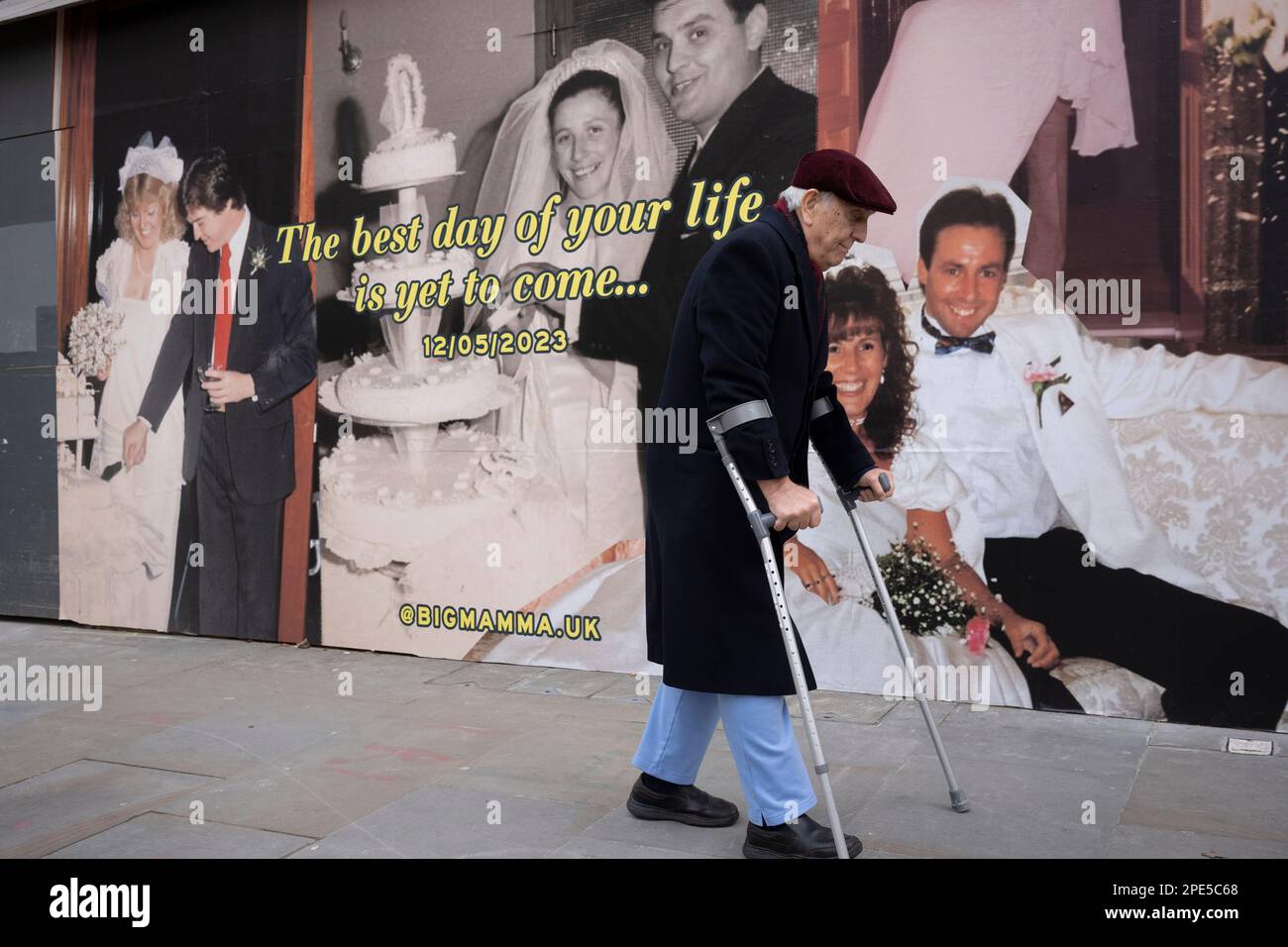 A disabled man walks with the help of crutches past a retail hoarding featuring a young bride and groom couple celebrating their wedding day, a picture of loyalty, dedication from youth to pension age, on 13th March 2023, in London, England. Stock Photo
