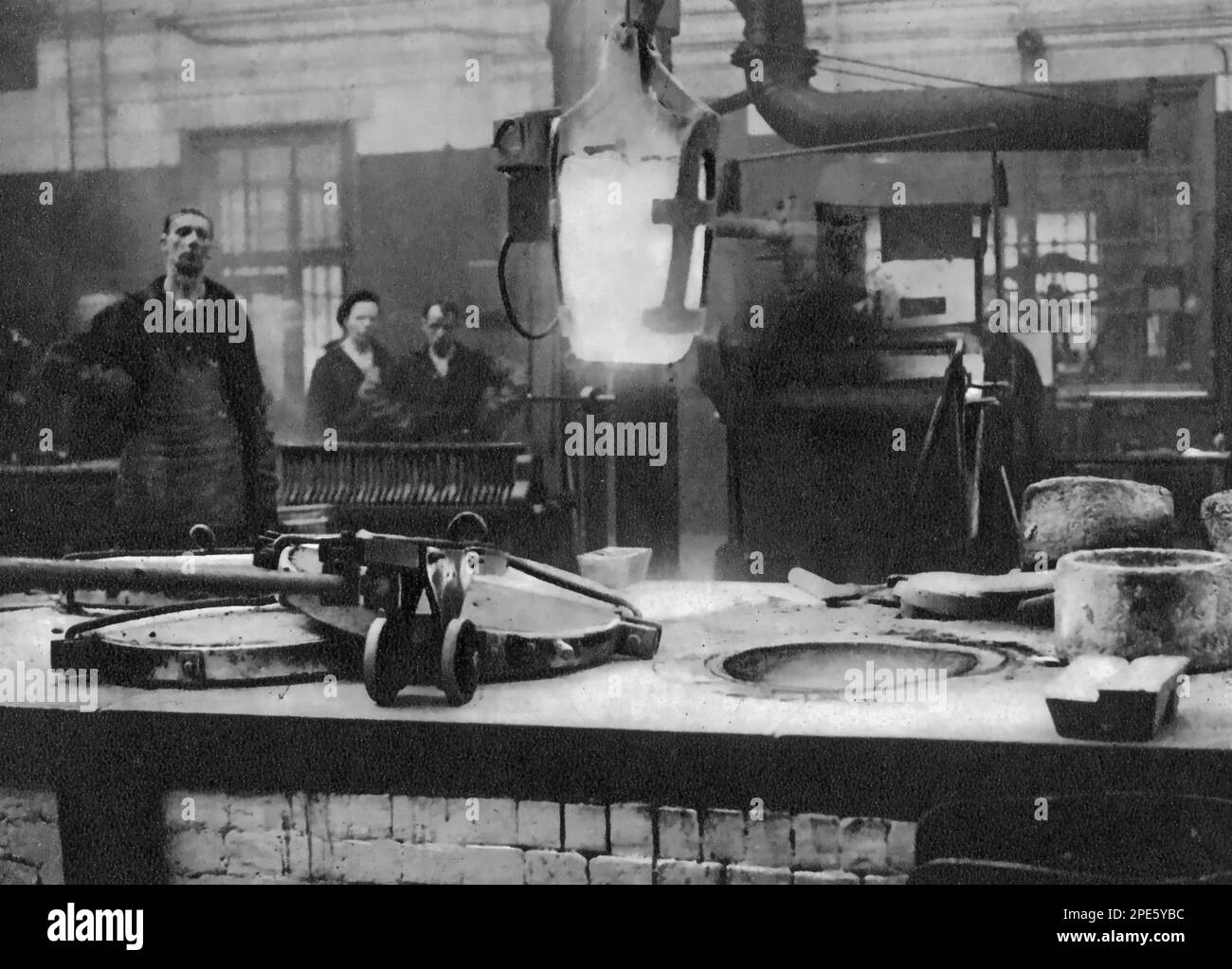 The Royal Mint, Tower Hill, London, c1933. A crucible of molten silver is lifted out of the furnace and carried to the machine that will stir the liquid metal before it is poured into moulds. Stock Photo