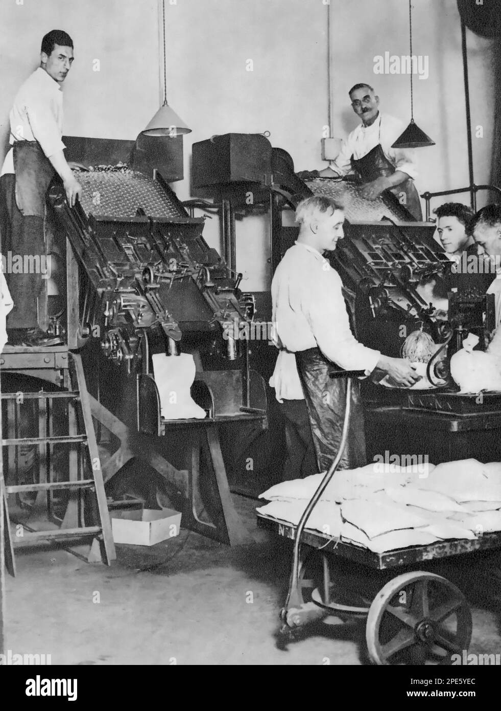 The Telling Room of the Royal Mint, Tower Hill, London, c1933. Men counting coins using an automated telling machine at The Royal Mint. Stock Photo