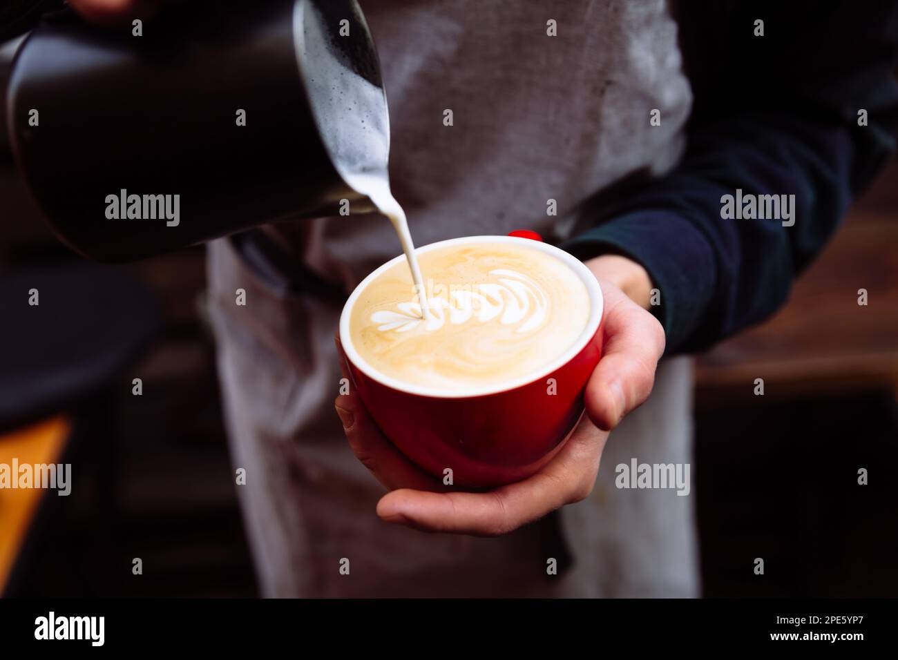 Flower Latte art. Barista pouring fresh milk into coffee. Stock Photo