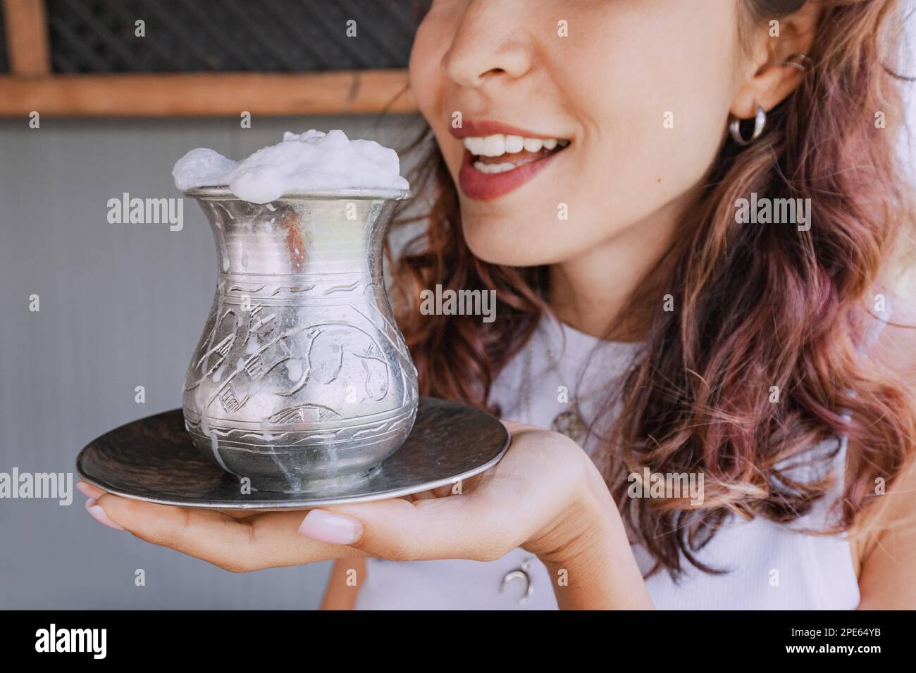Girl drinks a traditional Kazakh and Asian fermented milk drink from mare's milk - koumiss from a silver mug with foam Stock Photo