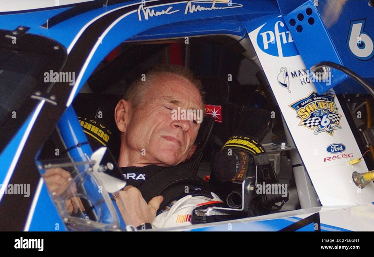 NASCAR driver Mark Martin gets strapped into his car during ...