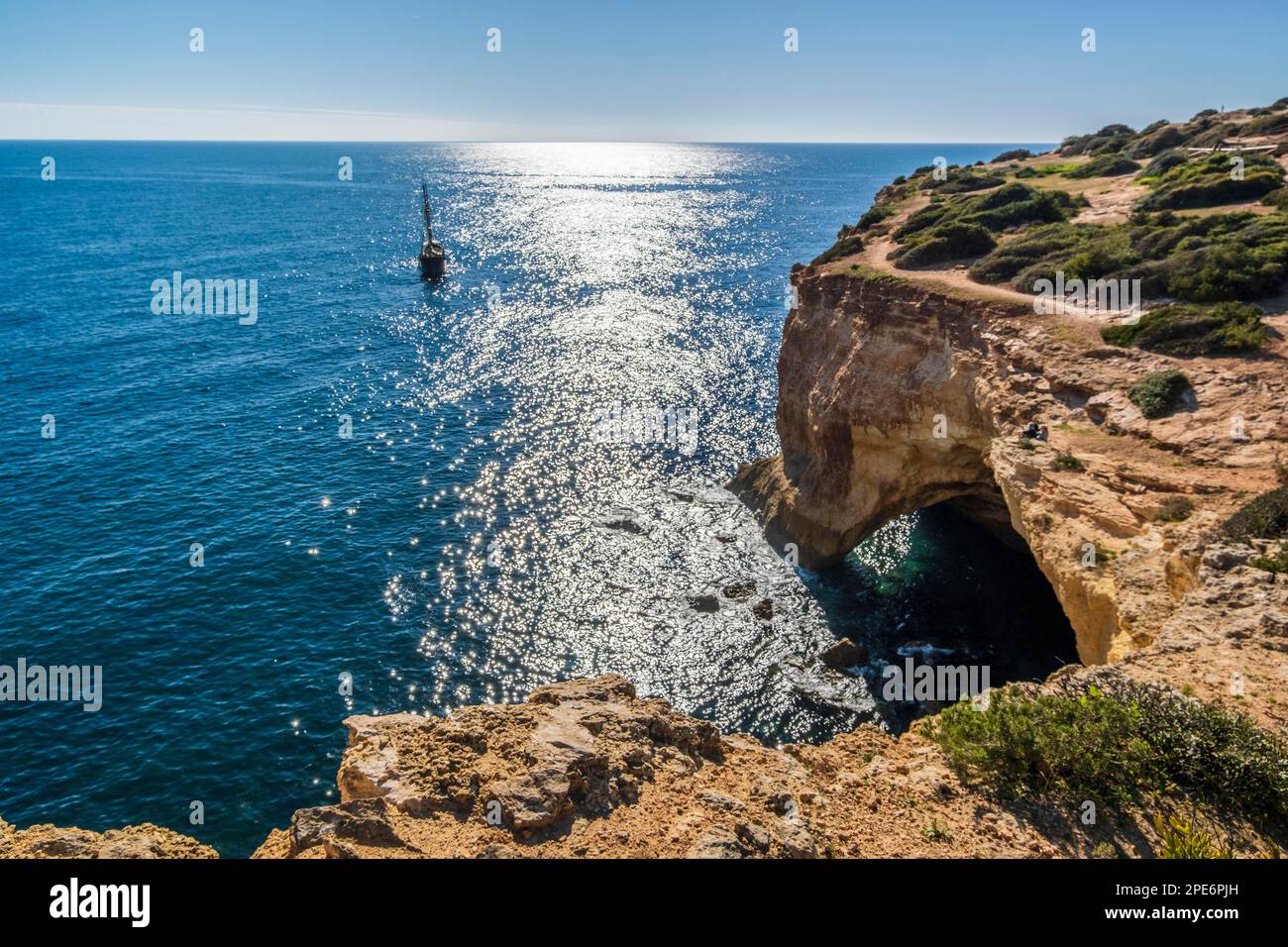Sailboat on the Atlantic Ocean, cliffs and arch at coast of Algarve, south of Portugal Stock Photo