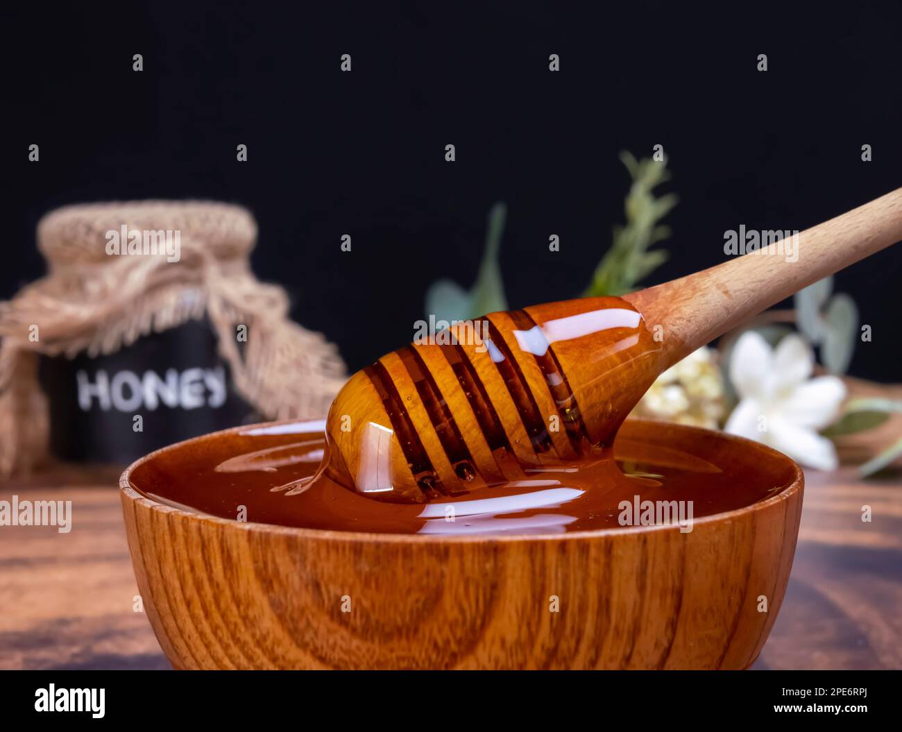 Honey spoon coming out of the bow full of honey. Honey contains many nutrients, antioxidants, improves heart health, wound care, offers antidepressant Stock Photo