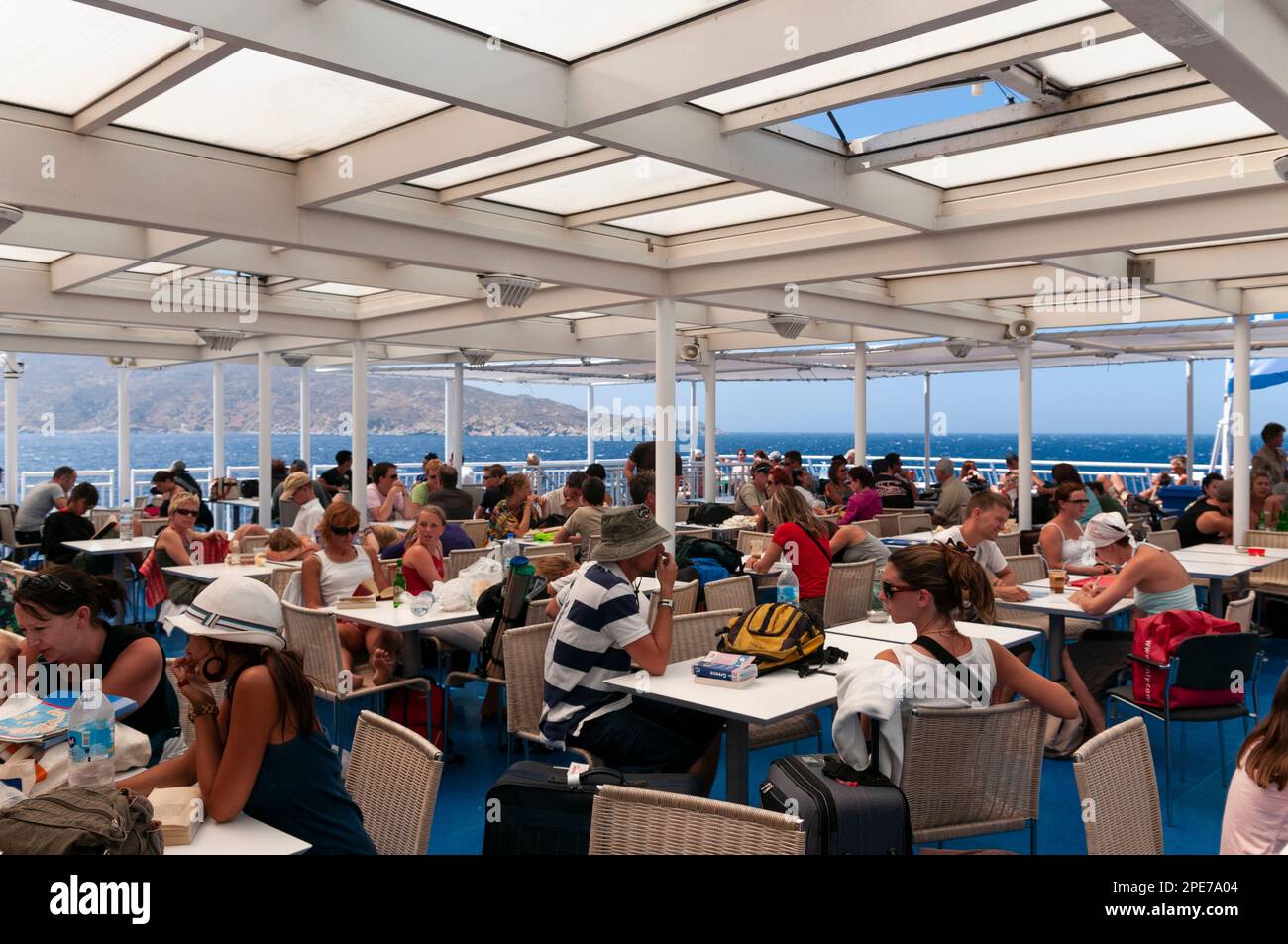 Large group of tourists on the open deck of a ship, sailing between the Cyclades islands in Greece Stock Photo