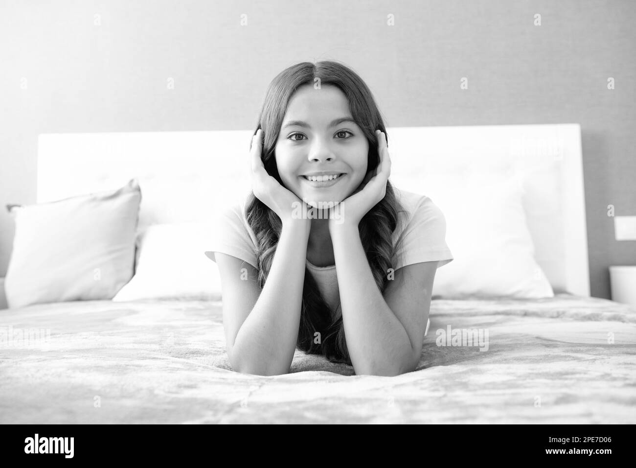 Happy teen girl, positive and smiling emotions. Teenager child girl daydreaming in bed, dreaming kids concept. Stock Photo