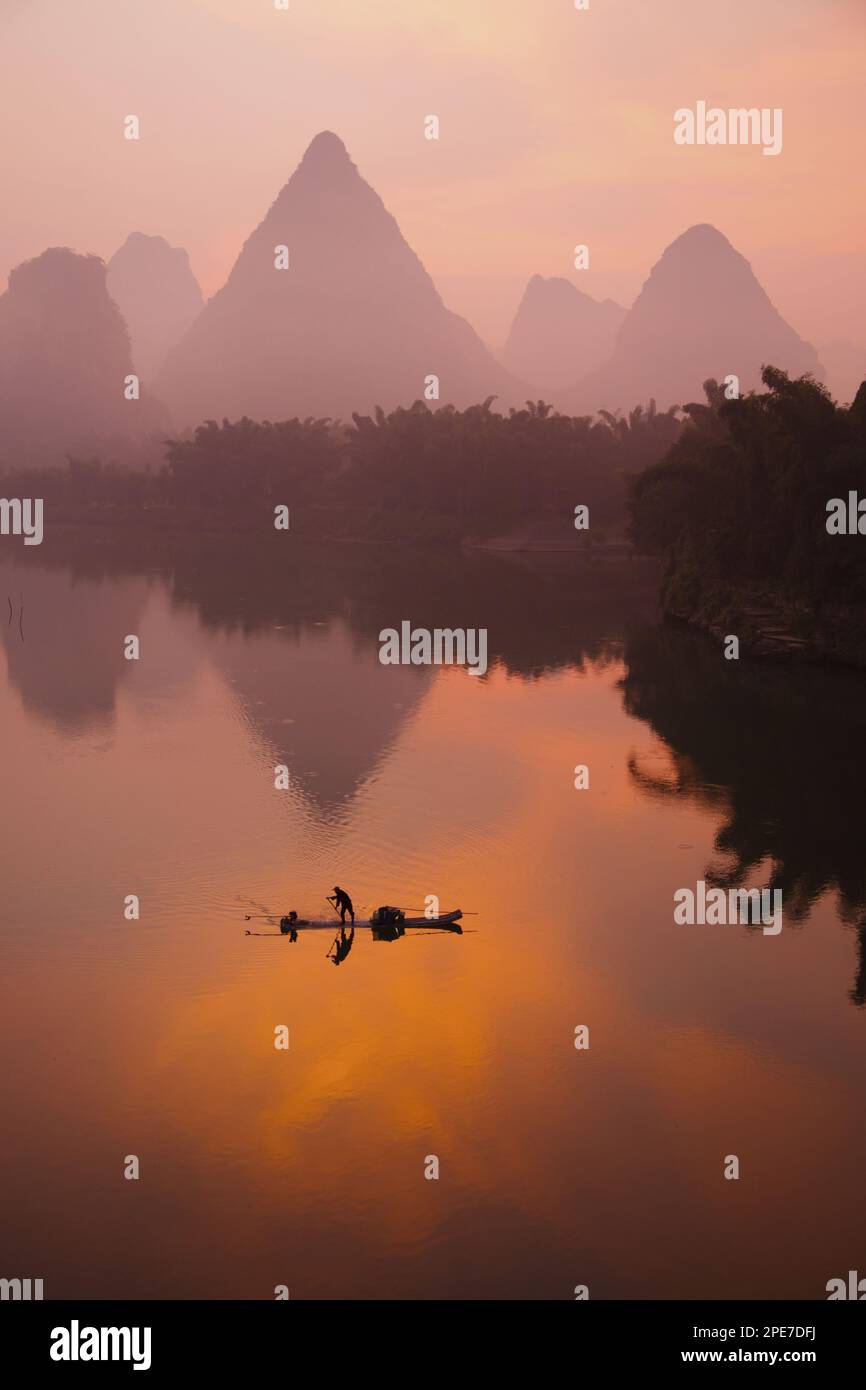 Traditional fisherman standing on a bamboo raft at sunrise, on a river in the karst area, Li River, Guilin, Guangxi Zhuang Autonomous Region, China Stock Photo