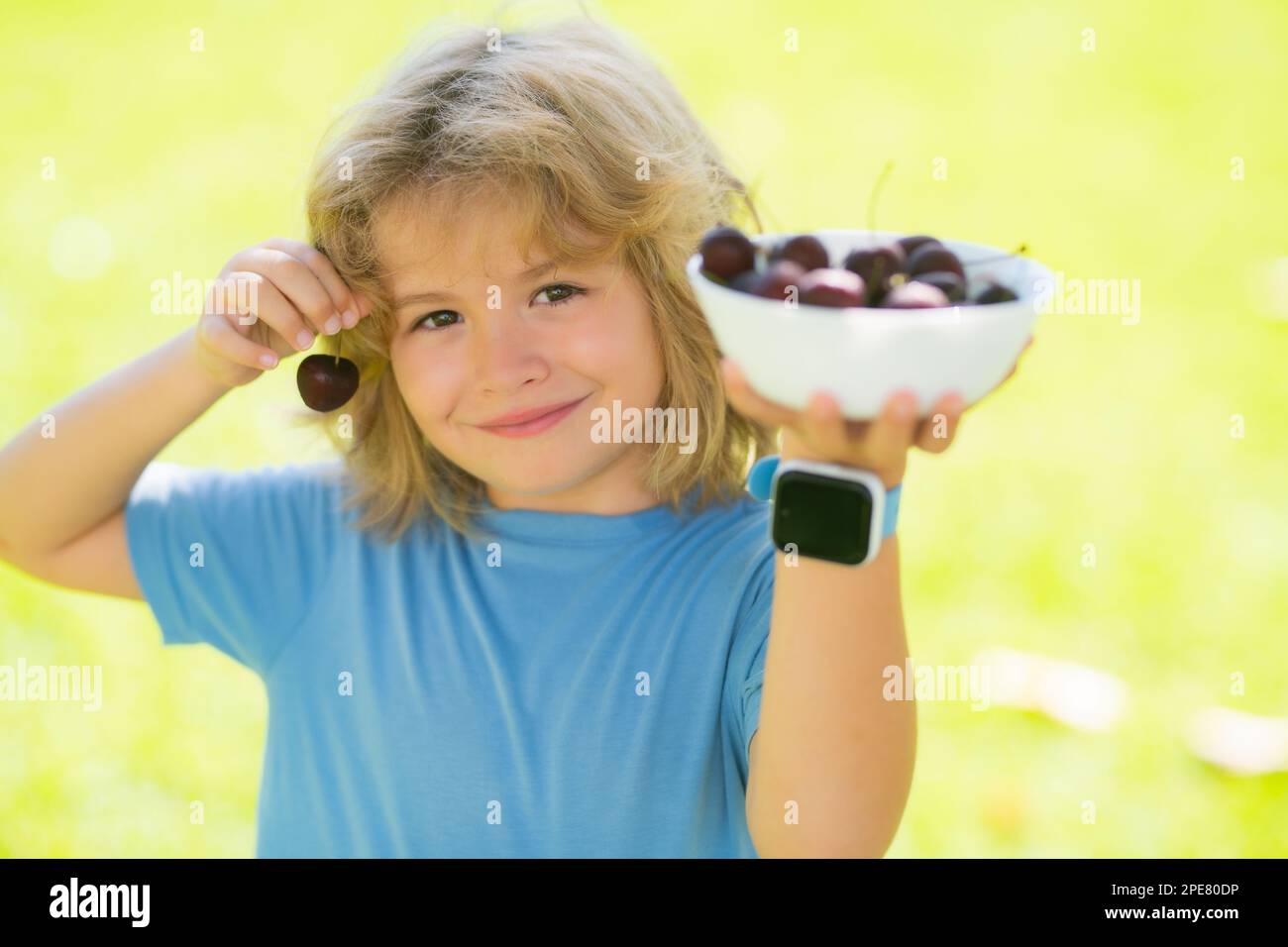 Summer child face. Child eat cherries in the summer. Kid is picking