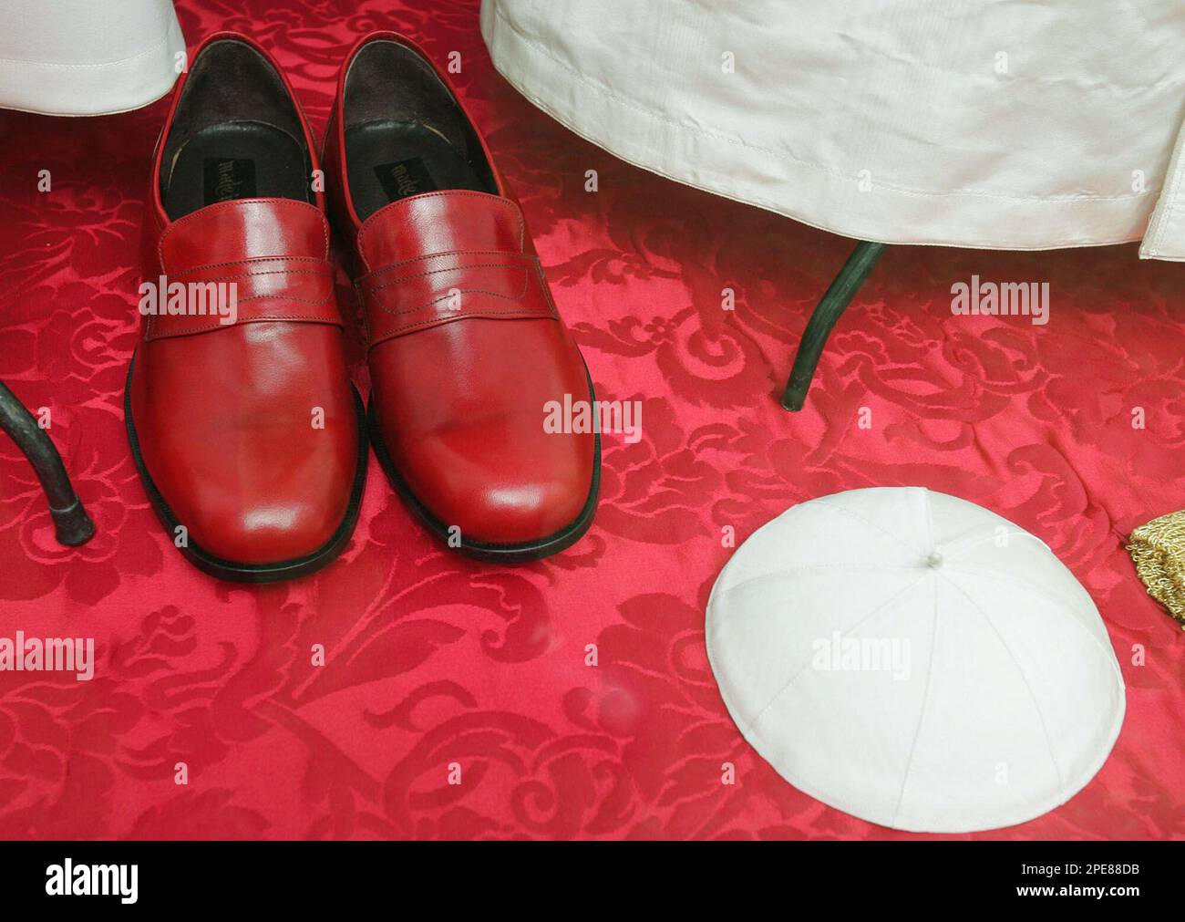 Papal burgundy shoes and white skull cap are on display in the