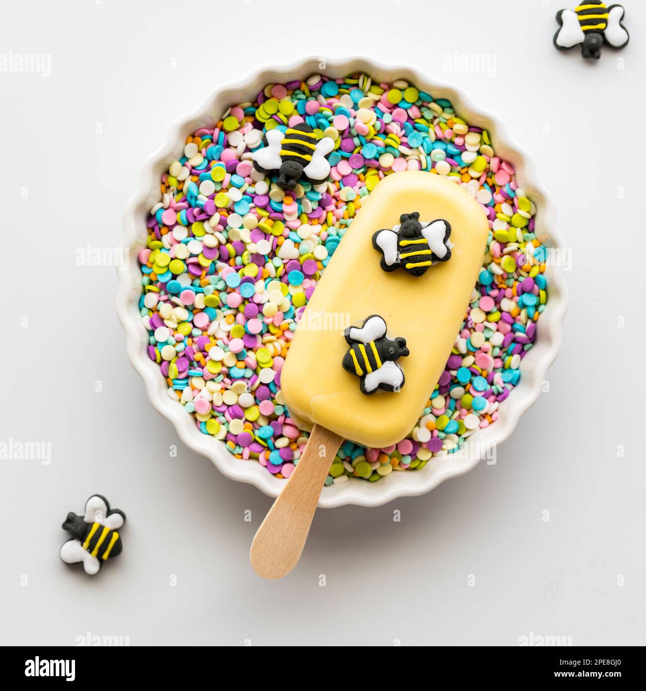 A homemade cakesicle decorated with edible bees in a bowl full of