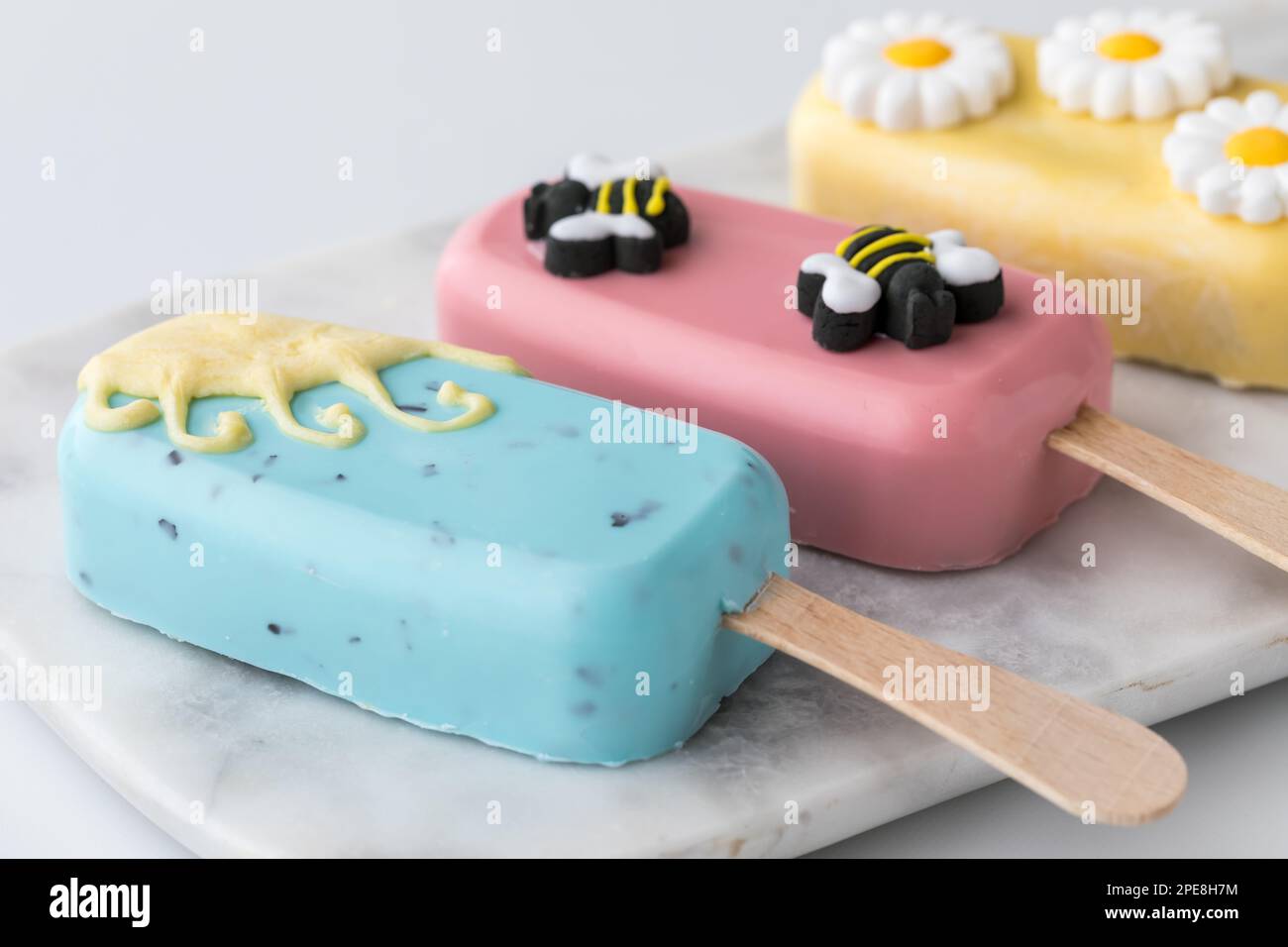 Homemade sweet cakesicles decorated for spring, laying on a marble slab