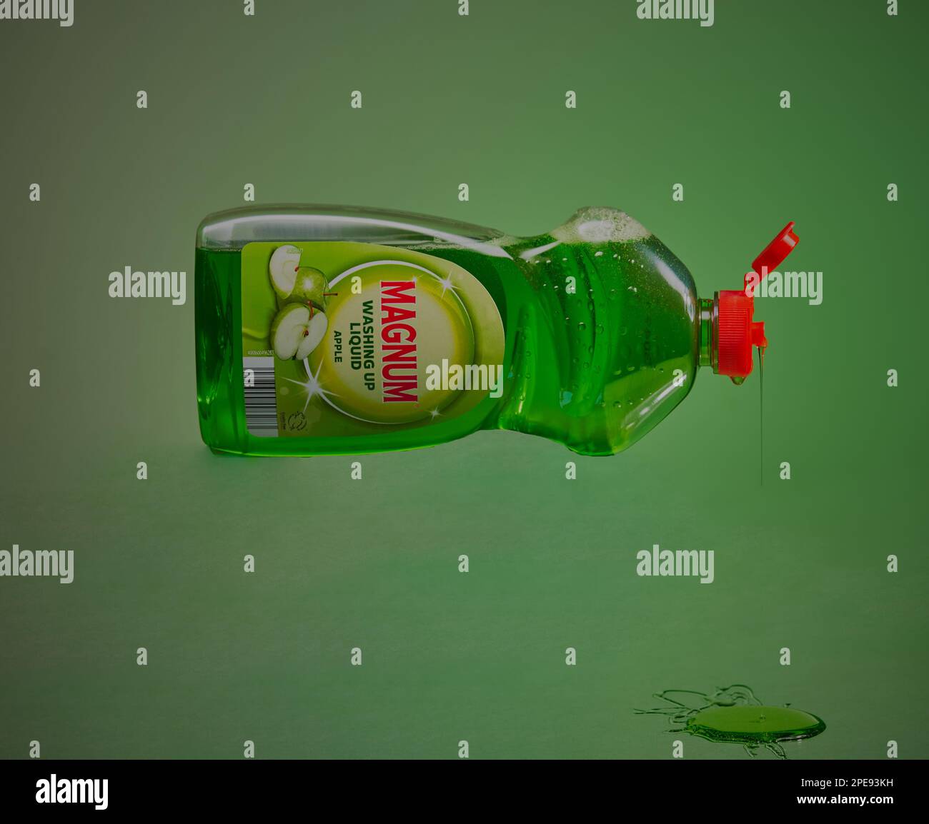 Bottle of washing up liquid tipped on its side in mid air with liquid pouring out of it,shot on