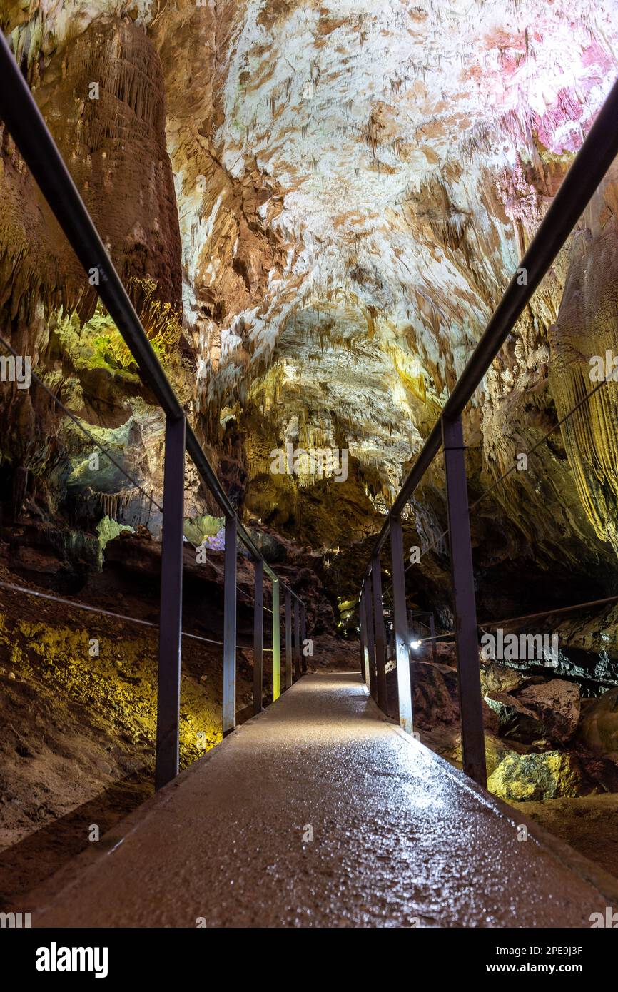 Pathway with metal railings through illuminated Prometheus Cave Natural