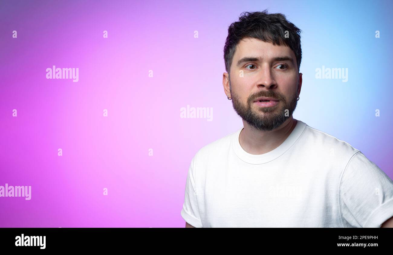 A handsome bearded pensive man with earrings with an anxious and confused look decision maker on a juicy gradient background. Anxiety and worry Stock Photo
